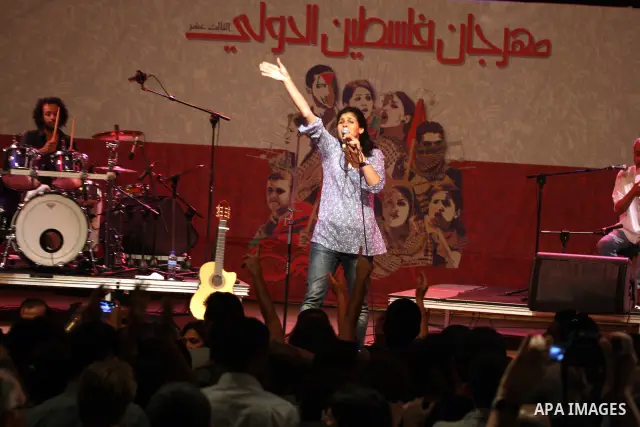Souad Massi, an Algerian singer and songwriter living in France, performs during the Palestine International Festival 2011, in the West Bank city of Ramallah, Tuesday, July 5, 2011. The Arabic on the wall on the backgrou...