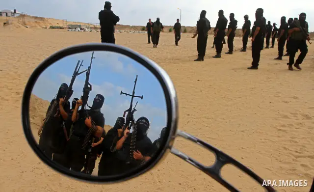 Some Palestinian militants from Al-Ansar brigades, the armed wing of Al-Ahrar movement, are reflected the mirror of a motorcycle as they demonstrate their skills during a drill in front of the media in Khan Younis in the...