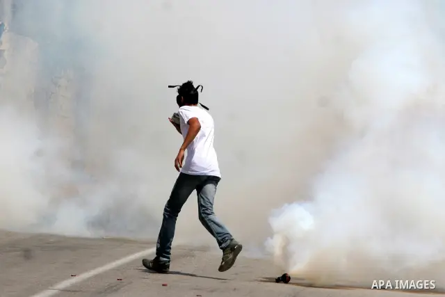 A Palestinian protester from the West Bank village of Nabi Salih, north of Ramallah, try to avoid tear gas shot by Israeli soldiers, on 08 July 2011, as they stand next to a symbolic flotilla boat, during the weekly Frid...