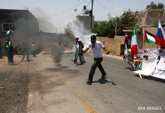 Palestinian protesters from the West Bank village of Nabi Salih, north of Ramallah, try to avoid tear gas shot by Israeli soldiers, on 08 July 2011, as they stand next to a symbolic flotilla boat, during the weekly Frida...