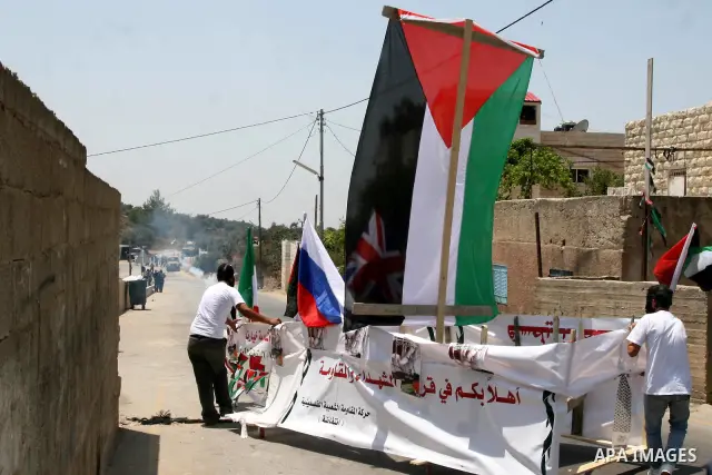 Palestinian protesters from the West Bank village of Nabi Salih, north of Ramallah, try to avoid tear gas shot by Israeli soldiers, on 08 July 2011, as they stand next to a symbolic flotilla boat, during the weekly Frida...