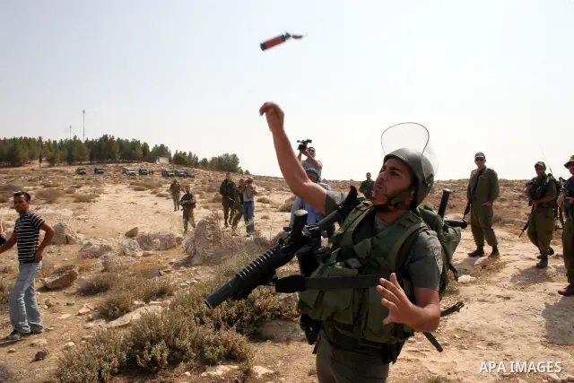 An Israeli soldier hurls tear gas canister towards Palestinian, foreign and Israeli protesters during a demonstration against the demolishing of farm land to be used in the construction of Jewish settlements near the exi...