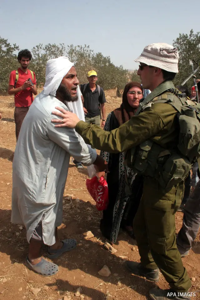 An Israeli soldier scuffles with Palestinian, foreign and Israeli protesters during a demonstration against the demolishing of farm land to be used in the construction of Jewish settlements near the existing Israeli sett...