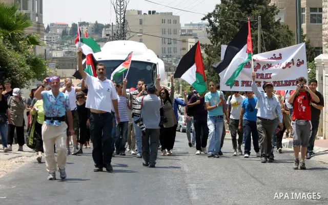 Israeli soldiers stand guard as Palestinians and foreigners protest in front of a section of Israel's controversial separation barrier at the main entrance of the West Bank city of Bethlehem on July 10, 2011, marking the...