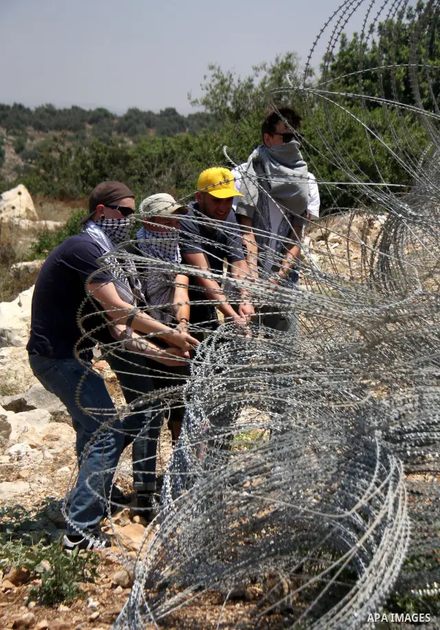 Palestinian and foreign protesters try to remove a part of Israeli separation barrier during a demonstration against Israeli occupation and settlements on July 11, 2011 in the village of Ezbet Tabeeb near the West Bank t...