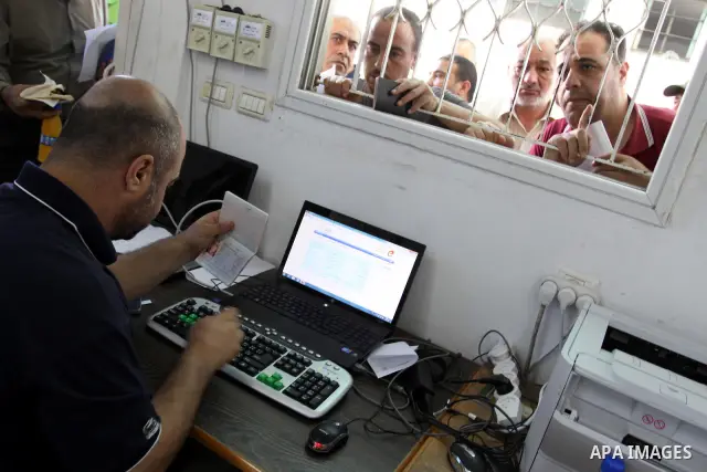 Palestinians wait behind the window to register their names with the Ministry of the Interior in the lists of travel in Gaza city on July 13, 2011. Where there are more than 20 thousand citizens need to travel abroad, Th...