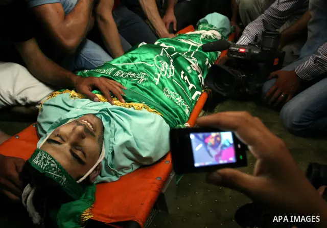 Palestinian mourners gather around the body of Ibrahim Sarhan, killed by Israeli military, during his funeral in the West Bank refugee camp of El Fara, north of Nablus, Wednesday, July 13, 2011. Sarhan was killed Wednesd...