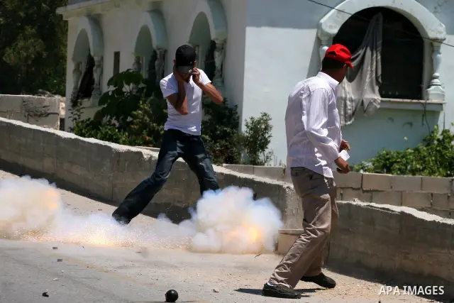 Palestinian protestors take cover from tear gas canisters fired by Israeli soldiers during clashes following a demonstration against Israeli occupation and settlements expansion, on July 15, 2011 in the West Bank village...