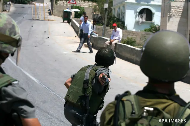 An Israeli soldier hurls tear gas canister toward Palestinian protestors during clashes following a demonstration against Israeli occupation and settlements expansion, on July 15, 2011 in the West Bank village of Nabi Sa...
