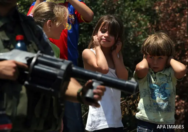 Palestinian children cover their heads as Israeli soldier fires tear gas canister during clashes with protesters following a demonstration against Israeli occupation and settlements expansion, on July 15, 2011 in the Wes...