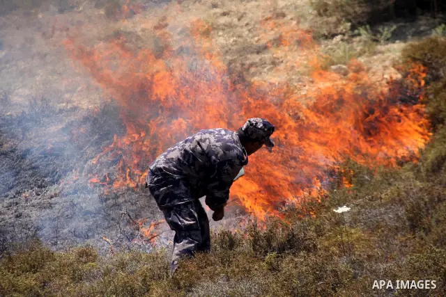 A Palestinian policeman tries to extinguish a fire on their land after Israeli settlers from the settlement of Yitshar burned the fields at the village of Burin near the West Bank town of Nablus, 15 July 2011. A group of...