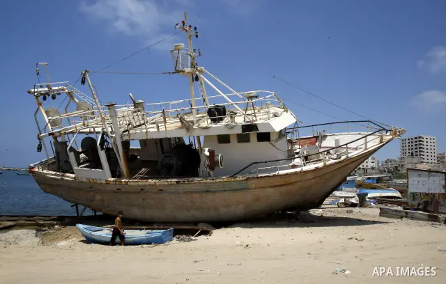 A Palestinian child walk near a boat at Gaza beach on July 16,2011. Photo by Mahmoud Nassar