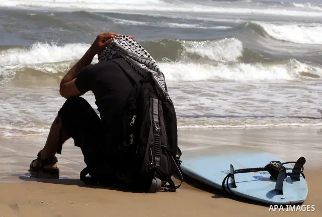 A Palestinian surfer sits on the beach during a practise session in Gaza City on July 17, 2011 . Photo by Mahmud Nassar