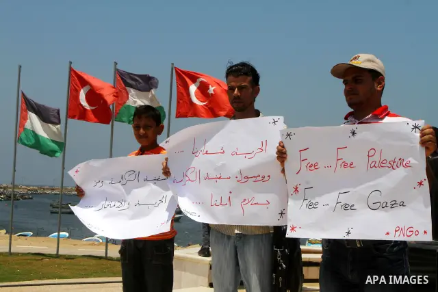 Palestinians hold banners at a protest at the Gaza seaport July 19, 2011. The Israeli navy on Tuesday boarded a French yacht carrying pro-Palestinian activists intending to sail to the blockaded Gaza Strip and forced it...