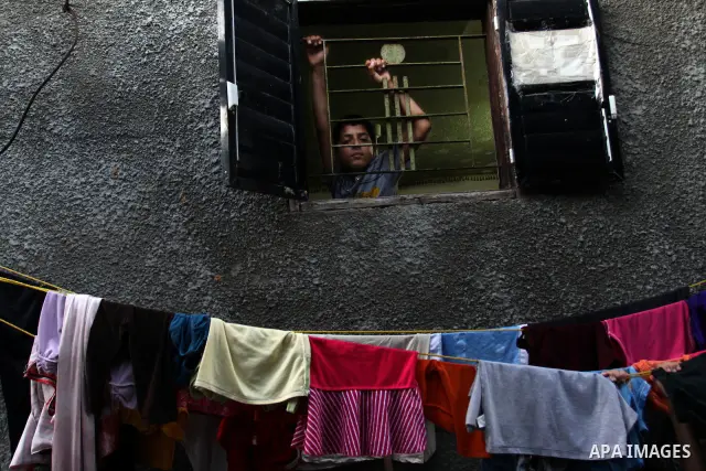 A Palestinian boy looks out from her house window in the Jabaliya refugee camp in the northern area of the Gaza Strip on July 21, 2011. The UN Relief and Works Agency (UNRWA) will reduce some of its services for Palestin...