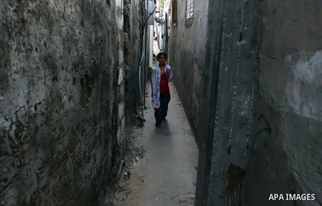 A Palestinian girl walks out from her house window in the Jabaliya refugee camp in the northern area of the Gaza Strip on July 21, 2011. The UN Relief and Works Agency (UNRWA) will reduce some of its services for Palesti...