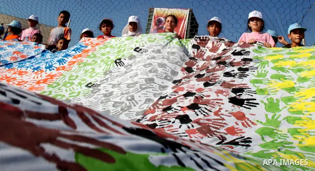 Palestinian children attend an event organised by the the United Nations Relief and Works Agency (UNRWA) in which they attempt to break the Guinness world record for the largest hand-print paint in Khan Yunis, southern G...