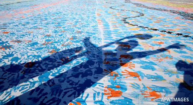 Palestinian children attend an event organised by the the United Nations Relief and Works Agency (UNRWA) in which they attempt to break the Guinness world record for the largest hand-print paint in Khan Yunis, southern G...