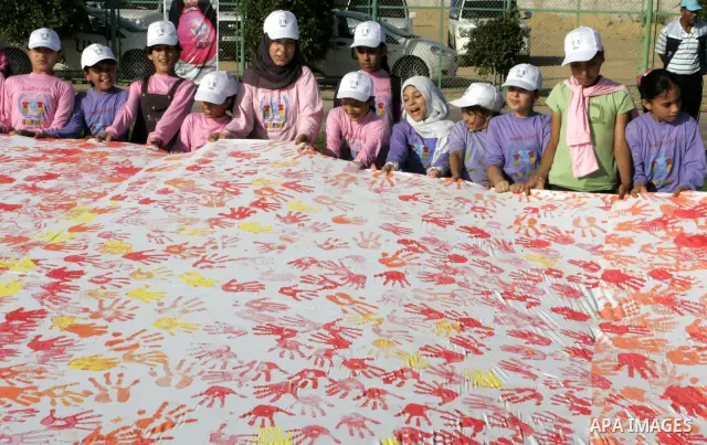 Palestinian children attend an event organised by the the United Nations Relief and Works Agency (UNRWA) in which they attempt to break the Guinness world record for the largest hand-print paint in Khan Yunis, southern G...