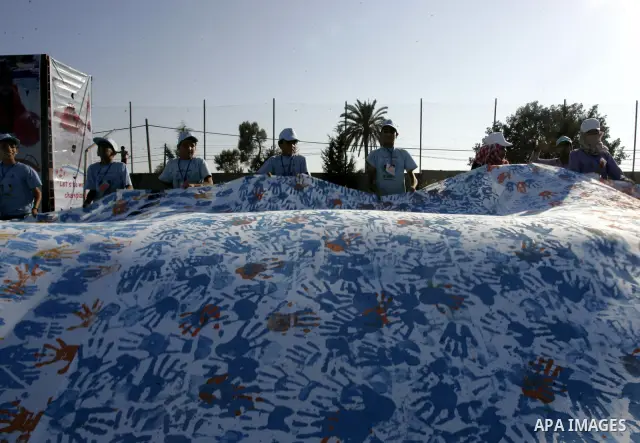 Palestinian children attend an event organised by the the United Nations Relief and Works Agency (UNRWA) in which they attempt to break the Guinness world record for the largest hand-print paint in Khan Yunis, southern G...