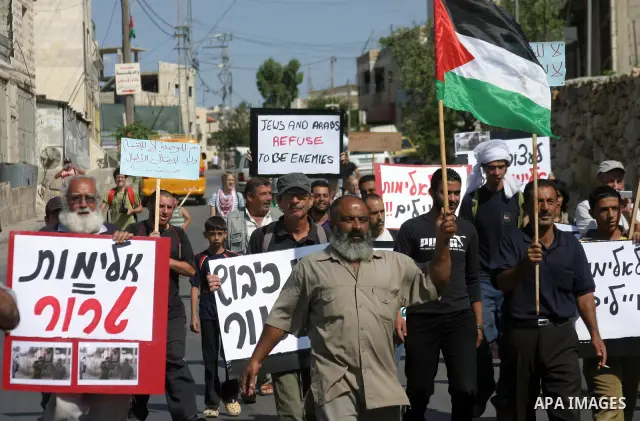 Protesters hold Palestinian flag and banners during a demonstration by Palestinian, Israeli, and foreign protesters in the West Bank village of Beit Omar, near Hebron Friday, July 22, 2011. The demonstration concerned a...