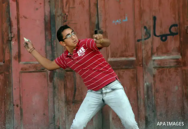 A Palestinian protester hurls stones toward Israeli soldiers during a demonstration by Palestinian, Israeli, and foreign protesters in the West Bank village of Beit Omar, near Hebron Friday, July 22, 2011. The demonstrat...