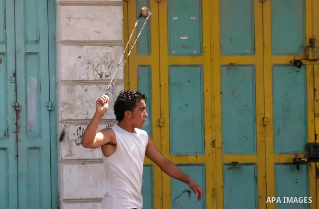 A Palestinian protester hurls stones toward Israeli soldiers during a demonstration by Palestinian, Israeli, and foreign protesters in the West Bank village of Beit Omar, near Hebron Friday, July 22, 2011. The demonstrat...
