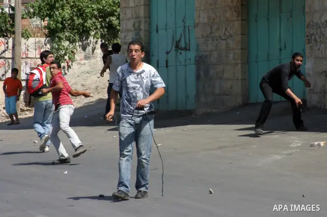A Palestinian protester hurls stones toward Israeli soldiers during a demonstration by Palestinian, Israeli, and foreign protesters in the West Bank village of Beit Omar, near Hebron Friday, July 22, 2011. The demonstrat...