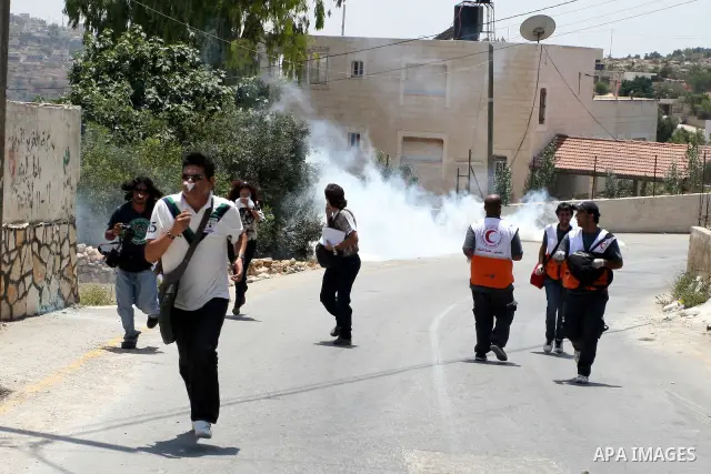 Palestinian protesters run for cover from tear gas canisters fired by Israeli soldiers in the West Bank village of Nabi Saleh, north of Ramallah, on July 22, 2011 during a weekly Friday protest against Israeli West Bank...