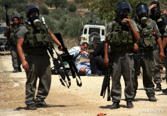 A Palestinian medic treats a man who was injured as Israeli forces fired tear gas at Palestinian protestors during a demonstration against the closure of a road during the second Intifada by Jewish settlers from the near...