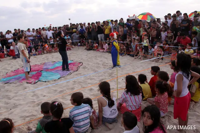 Palestinians watch young clowns as they demonstrate their skills on the beach in Gaza City Friday, July 22, 2011. Photo by Mohammed Asad