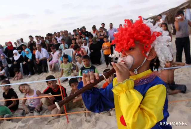 Palestinians watch young clowns as they demonstrate their skills on the beach in Gaza City Friday, July 22, 2011. Photo by Mohammed Asad