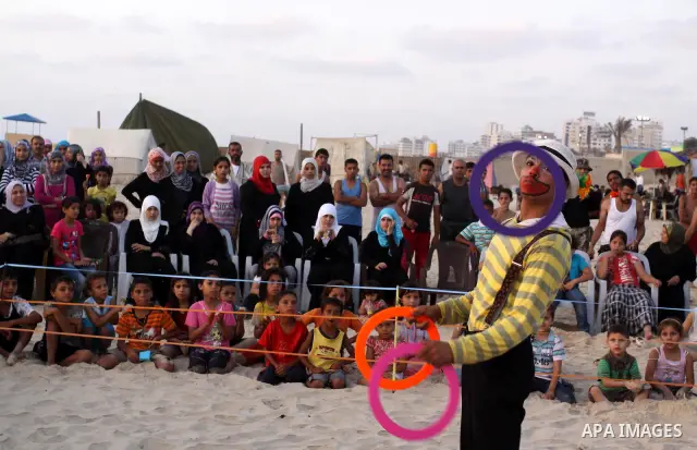 Palestinians watch young clowns as they demonstrate their skills on the beach in Gaza City Friday, July 22, 2011. Photo by Mohammed Asad