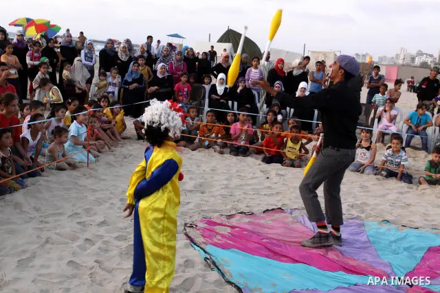 Palestinians watch young clowns as they demonstrate their skills on the beach in Gaza City Friday, July 22, 2011. Photo by Mohammed Asad