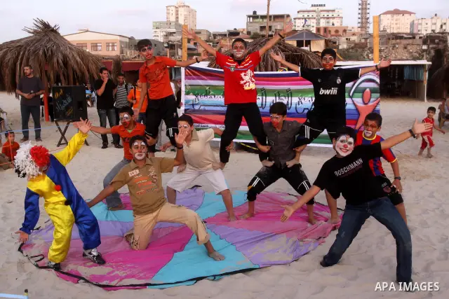Palestinians watch young clowns as they demonstrate their skills on the beach in Gaza City Friday, July 22, 2011. Photo by Mohammed Asad