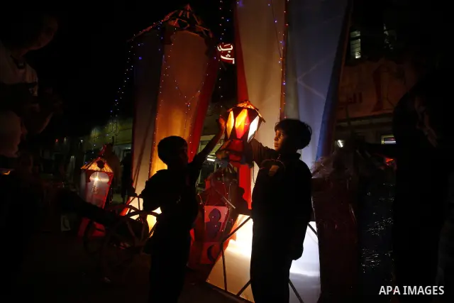 Palestinian children attach a small lantern next to a giant paper lantern, traditionally used as decoration during the Muslim holy month of Ramadan, in Gaza City on July 23, 2011. Photo by Mahmud Nassar