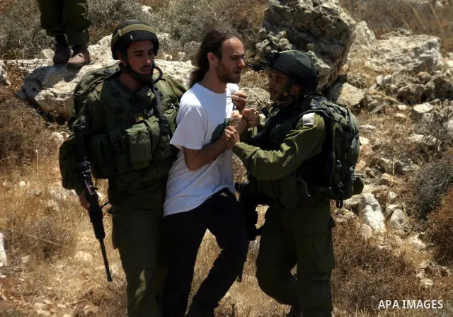 An Israeli soldier detains a protester during a demonstration against Israel's controversial separation barrier in the West Bank village of Beit Omar, near Hebron, 23 July 2011. Israel says the network of steel and concr...