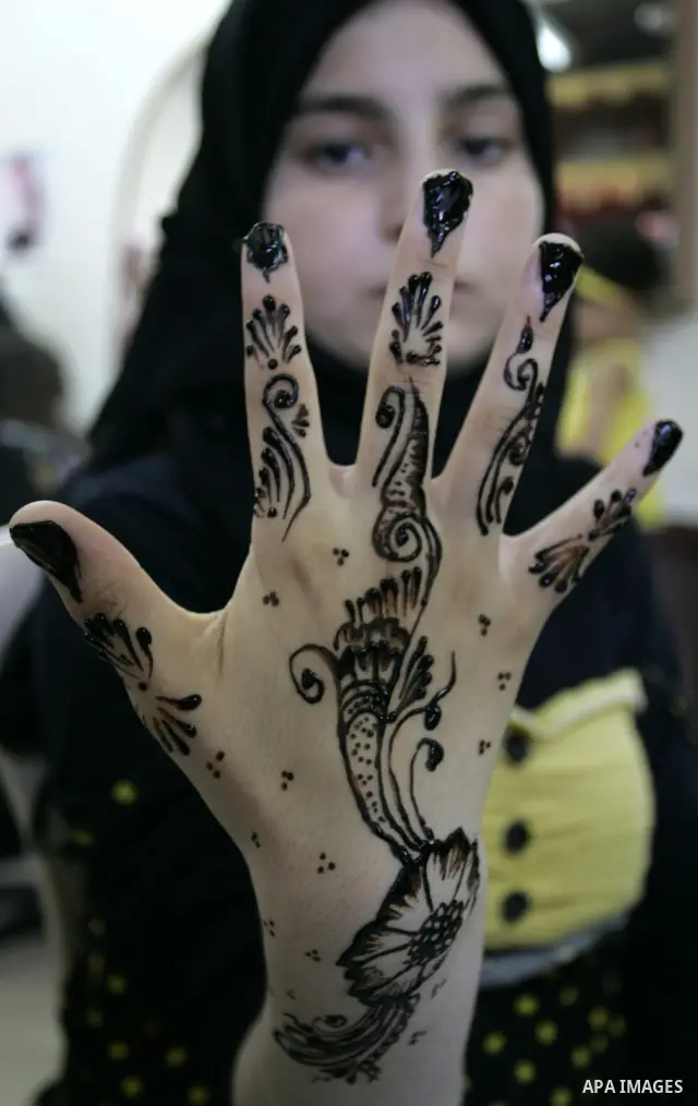 A Palestinian woman applies henna on the hand of a girl during a summer camp organised by the Ministry of Youth and Sports in Rafah, southern Gaza Strip, on July 23, 2011. Photo by Abed Rahim Khatib