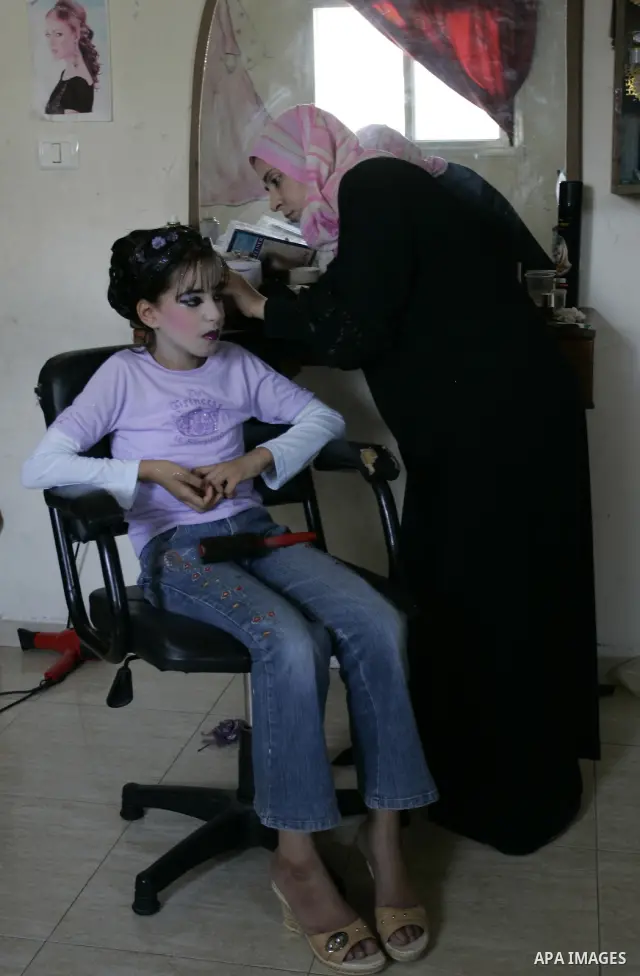 A Palestinian woman applies makeup on the face of a girl during a summer camp organised by the Ministry of Youth and Sports in Rafah, southern Gaza Strip, on July 23, 2011. Photo by Abed Rahim Khatib