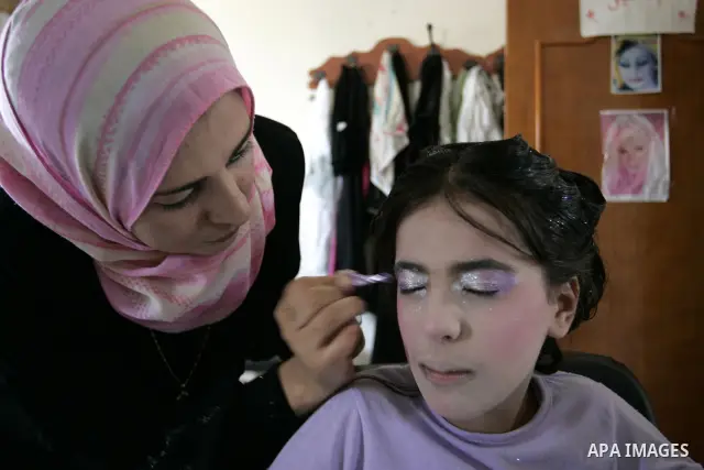 A Palestinian woman applies makeup on the face of a girl during a summer camp organised by the Ministry of Youth and Sports in Rafah, southern Gaza Strip, on July 23, 2011. Photo by Abed Rahim Khatib