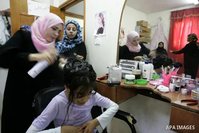 A Palestinian woman applies makeup on the face of a girl during a summer camp organised by the Ministry of Youth and Sports in Rafah, southern Gaza Strip, on July 23, 2011. Photo by Abed Rahim Khatib