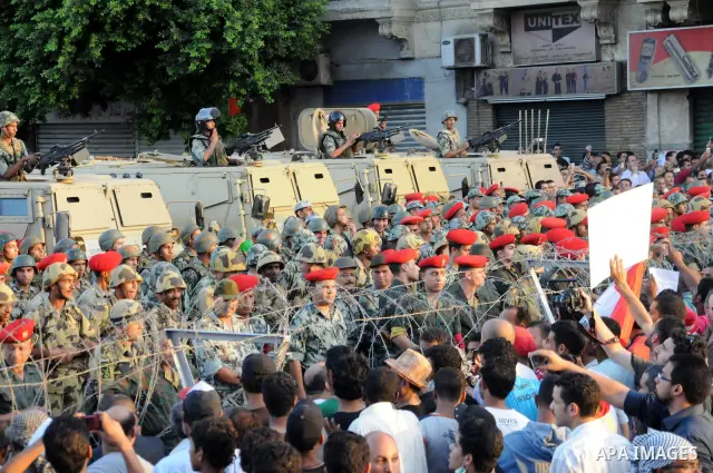 Egyptian soldiers stand guard behind barbed wire as protesters demonstrate outside the defence ministry, the headquarters of the Supreme Council of the Armed Forces, in Cairo on July 23, 2011 to show their anger at the r...