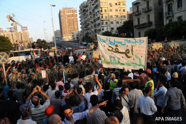 Egyptian soldiers stand guard behind barbed wire as protesters demonstrate outside the defence ministry, the headquarters of the Supreme Council of the Armed Forces, in Cairo on July 23, 2011 to show their anger at the r...