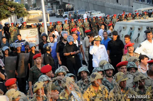 Egyptian soldiers stand guard behind barbed wire as protesters demonstrate outside the defence ministry, the headquarters of the Supreme Council of the Armed Forces, in Cairo on July 23, 2011 to show their anger at the r...