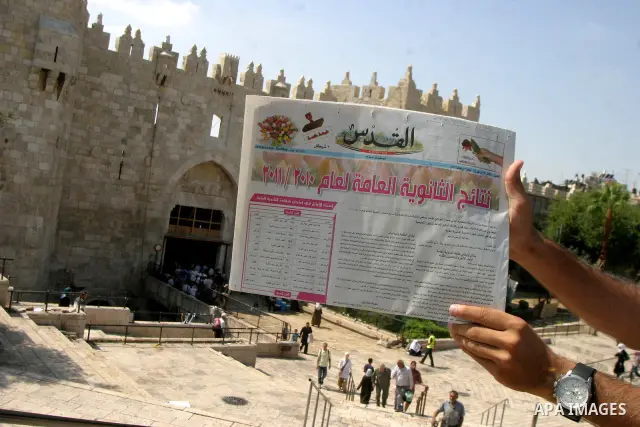 Palestinian students read a local newspaper as they look for their results of final high school exams, known as "Tawjihi" in Jerusalem's old city on July 24,2011.. Photo by Mahfouz Abu Turk