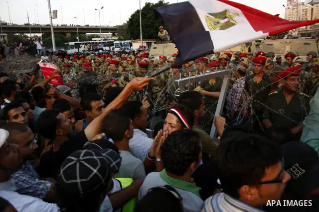 Egyptian soldiers stand guard behind barbed wire as protesters demonstrate outside the defence ministry, the headquarters of the Supreme Council of the Armed Forces, in Cairo on July 23, 2011 to show their anger at the r...