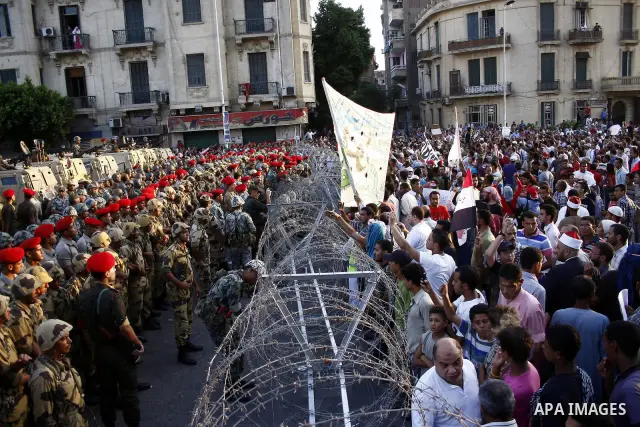 Egyptian soldiers stand guard behind barbed wire as protesters demonstrate outside the defence ministry, the headquarters of the Supreme Council of the Armed Forces, in Cairo on July 23, 2011 to show their anger at the r...