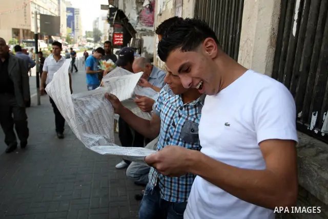 Palestinian students read a local newspaper as they look for their results of final high school exams, known as "Tawjihi" in the West Bank city of Ramallah on July 24,2011. Photo by Issam Rimawi