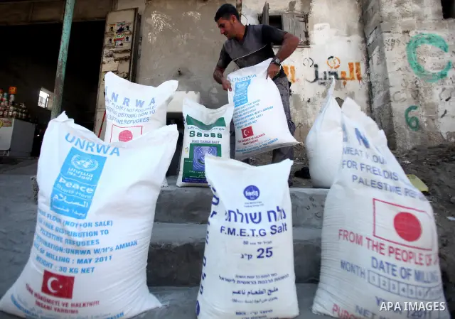 A Palestinian man holds a sack of flour at monthly food aid at a UN distribution center at the Shatie refugee camp, western Gaza city, 24 July 2011. The UN Relief and Works Agency (UNRWA) will reduce some of its services...