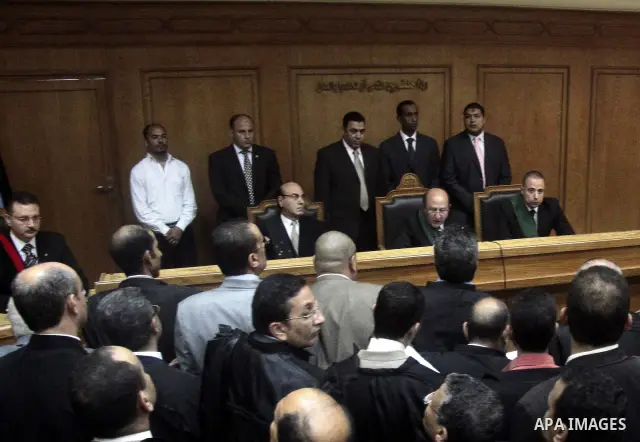 Journalists and bodyguards stand in the Cairo court room as defendants are kept behind bars, including Egypt's former Interior Minister Habib el-Adly, seen behind bars 3rd left, during their trial on charges relating to...